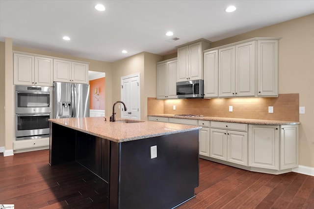 kitchen with light stone countertops, stainless steel appliances, dark wood-style flooring, and a sink