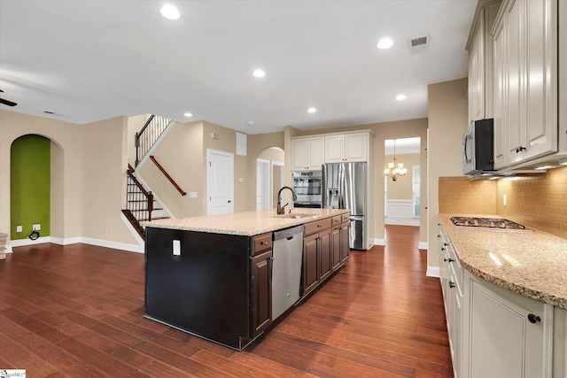 kitchen with a sink, stainless steel appliances, tasteful backsplash, visible vents, and arched walkways