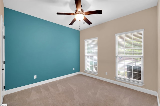 carpeted spare room with baseboards and a ceiling fan