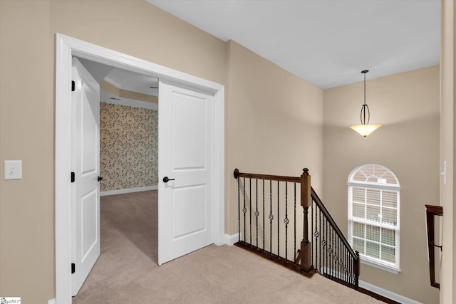 corridor featuring an upstairs landing, light colored carpet, and baseboards