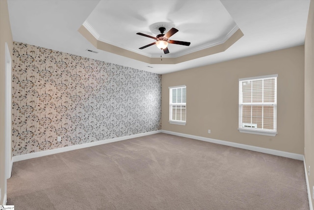 unfurnished room featuring carpet, a raised ceiling, ceiling fan, and ornamental molding
