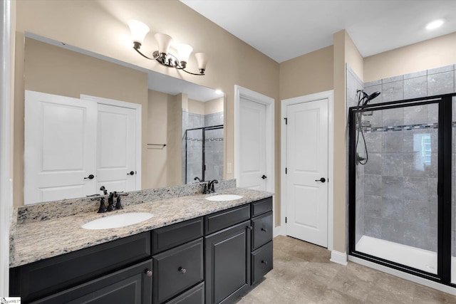 full bathroom featuring a stall shower, a notable chandelier, double vanity, and a sink