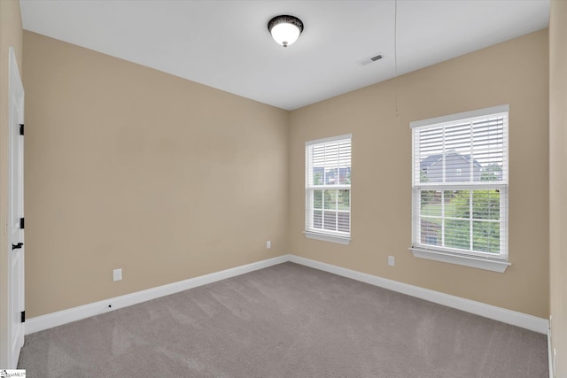 spare room featuring visible vents, carpet, and baseboards