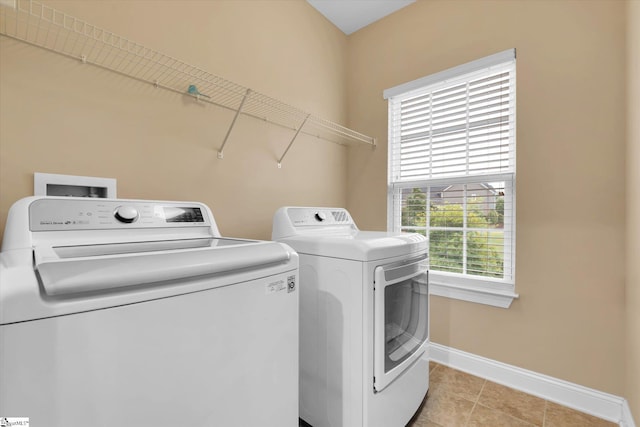washroom featuring baseboards, light tile patterned floors, separate washer and dryer, and laundry area