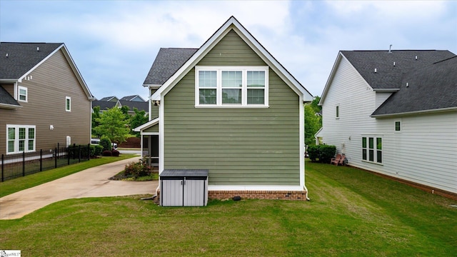 rear view of property featuring a lawn and fence