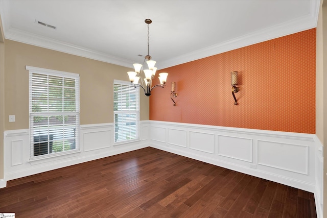empty room with crown molding, visible vents, a wainscoted wall, dark wood-type flooring, and a notable chandelier