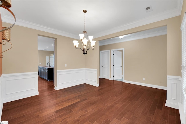 unfurnished dining area featuring a sink, visible vents, dark wood-style floors, a notable chandelier, and wainscoting