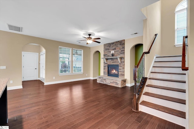 unfurnished living room with a fireplace, stairway, visible vents, and ceiling fan