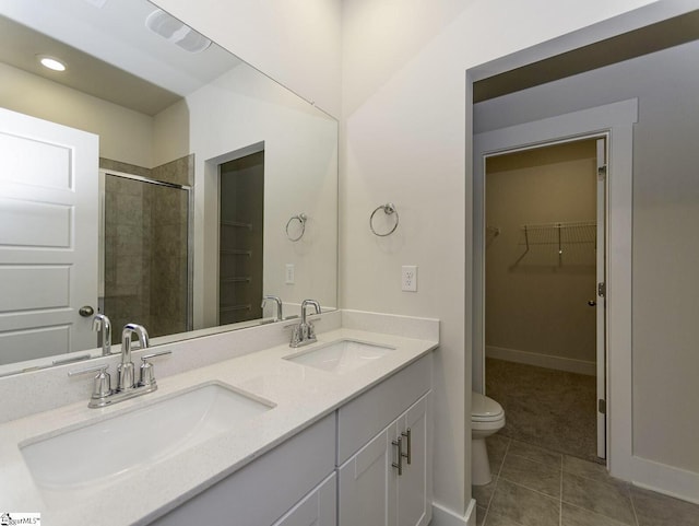 full bathroom featuring a walk in closet, tile patterned flooring, a stall shower, and a sink