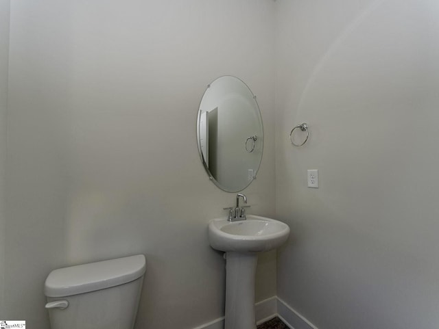 half bathroom featuring baseboards and toilet