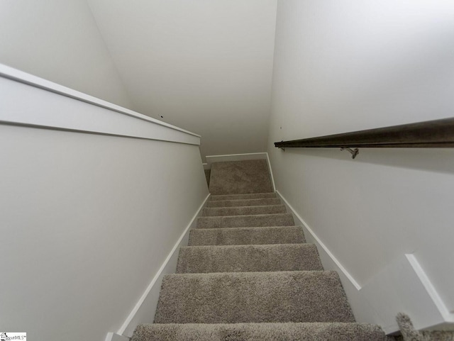 staircase featuring baseboards, lofted ceiling, and carpet