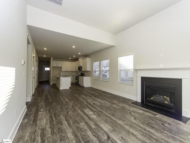 unfurnished living room featuring dark wood finished floors, baseboards, visible vents, and a fireplace with flush hearth