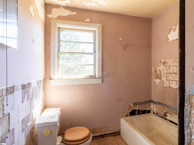 2006 E N St, Greenville, SC 29607 - bathroom featuring toilet, tile walls, a tub to relax in, and a healthy amount of sunlight