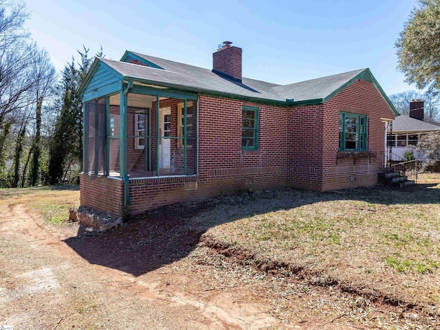 2006 E N St, Greenville, SC 29607 - view of property exterior with a lawn, a chimney, brick siding, and a sunroom