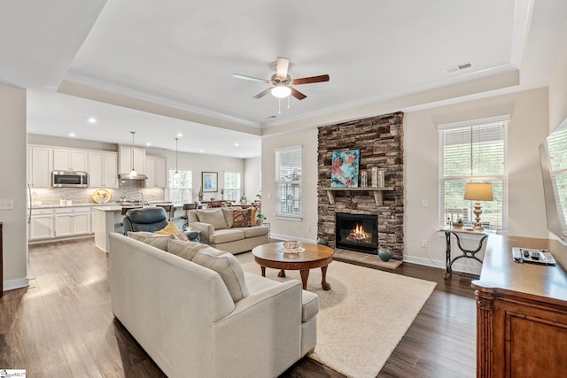 living area with visible vents, a healthy amount of sunlight, a ceiling fan, and a tray ceiling