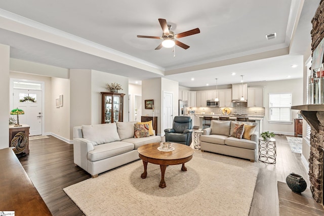 living room with visible vents, ceiling fan, a tray ceiling, recessed lighting, and dark wood-type flooring