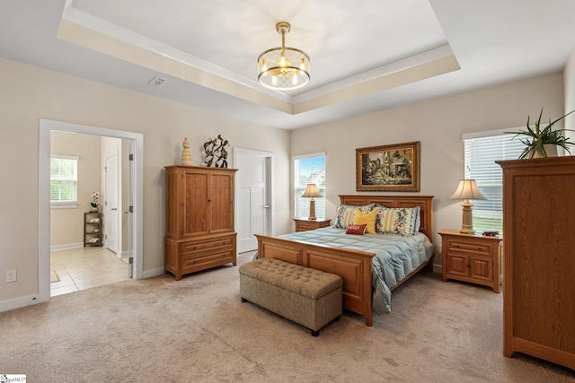 bedroom featuring a chandelier, baseboards, a raised ceiling, and light carpet