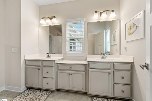 full bathroom with double vanity, tile patterned floors, baseboards, and a sink