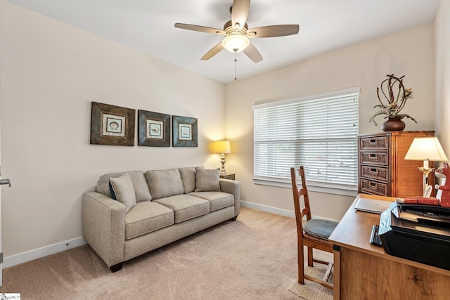 office featuring a ceiling fan, light colored carpet, and baseboards