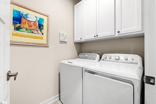 clothes washing area with baseboards, cabinet space, and washer and clothes dryer