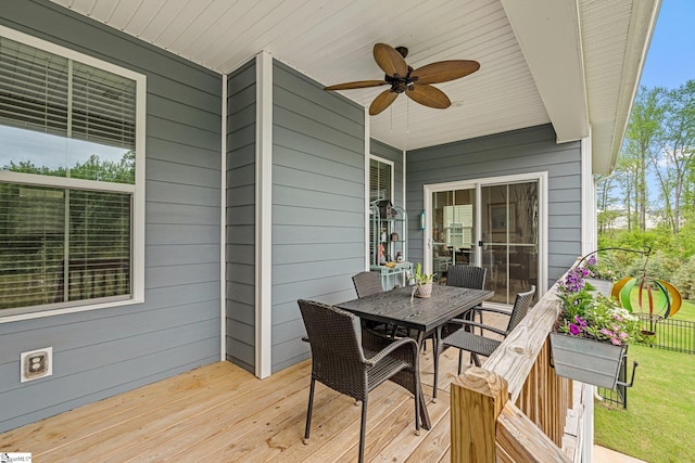 wooden deck with outdoor dining space and ceiling fan