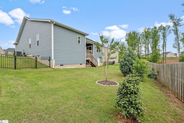 rear view of house featuring stairway, a fenced backyard, a yard, and crawl space