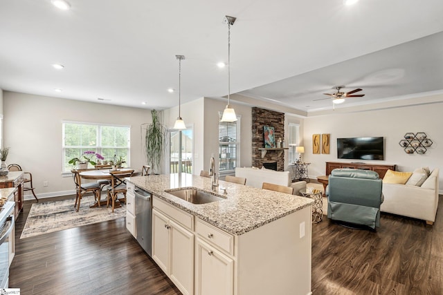 kitchen featuring a sink, a stone fireplace, appliances with stainless steel finishes, and dark wood-style flooring