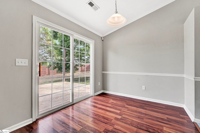 spare room featuring lofted ceiling, crown molding, visible vents, baseboards, and wood finished floors