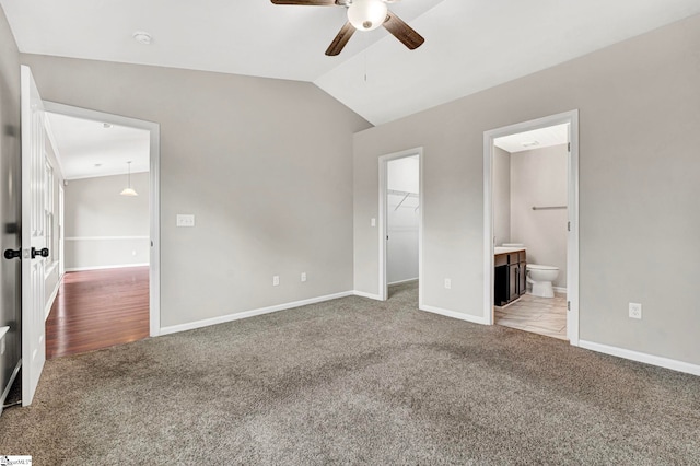 unfurnished bedroom featuring lofted ceiling, a spacious closet, carpet flooring, and baseboards