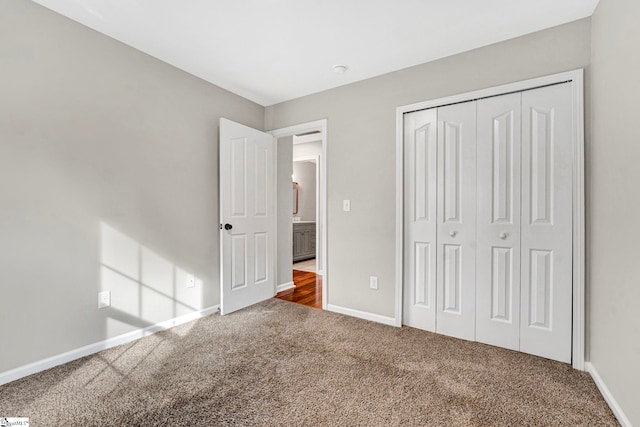unfurnished bedroom with a closet, baseboards, and carpet floors