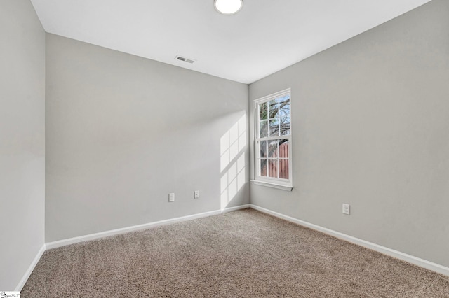 spare room featuring baseboards, visible vents, and carpet