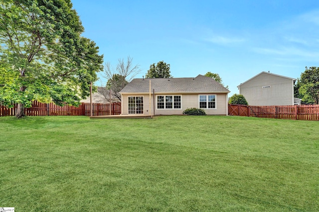 back of property with a fenced backyard and a yard