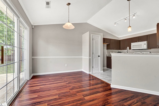 kitchen with wood finished floors, white microwave, dark brown cabinets, visible vents, and lofted ceiling