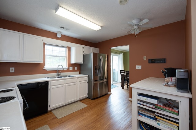 kitchen featuring a sink, visible vents, light wood-type flooring, black dishwasher, and stainless steel fridge with ice dispenser