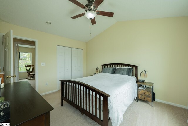 bedroom with a closet, baseboards, vaulted ceiling, and light carpet
