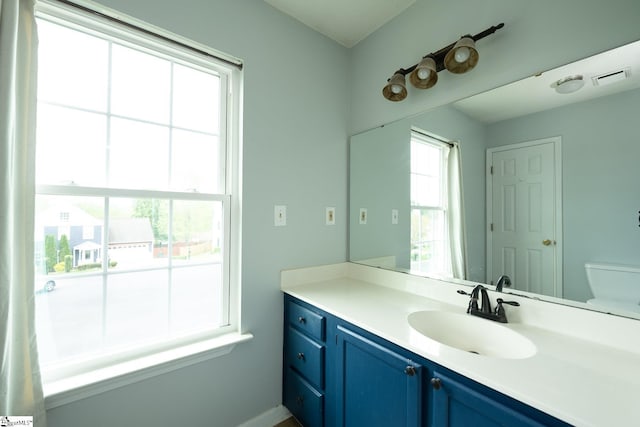 bathroom featuring toilet, visible vents, vanity, and baseboards