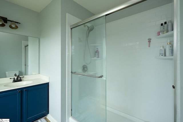bathroom featuring a shower stall, toilet, and vanity