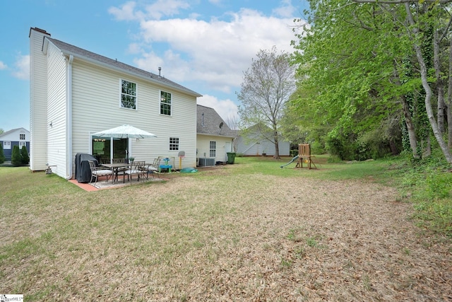 rear view of house with central AC, a chimney, a lawn, and a patio area