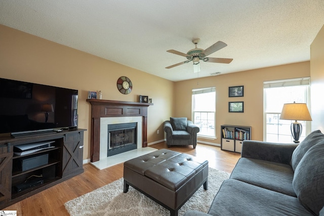 living room with a fireplace with flush hearth, wood finished floors, and a ceiling fan