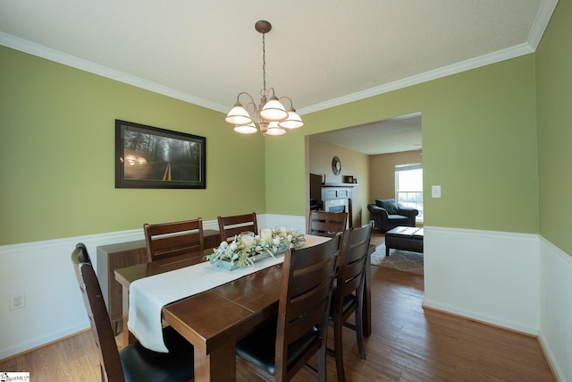 dining room with wood finished floors, crown molding, and a notable chandelier