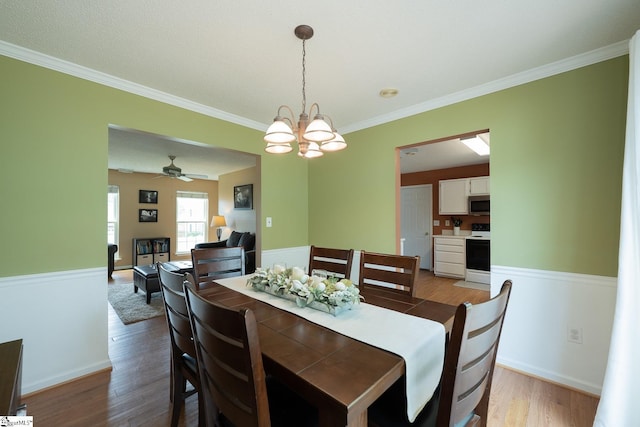 dining room featuring crown molding, baseboards, light wood-style flooring, and ceiling fan with notable chandelier