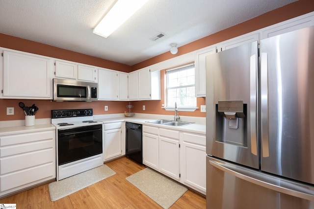 kitchen with stainless steel appliances, white cabinets, light wood finished floors, a sink, and visible vents