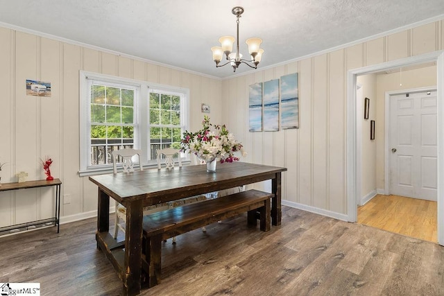dining area with a chandelier, baseboards, wood finished floors, and crown molding