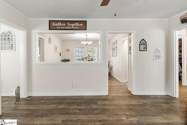 interior space with ceiling fan with notable chandelier, ornamental molding, dark wood-style floors, and baseboards