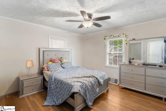 bedroom featuring crown molding, visible vents, wood finished floors, and baseboards