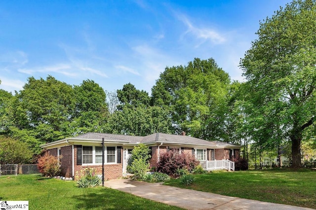 ranch-style house featuring a chimney, brick siding, fence, and a front lawn