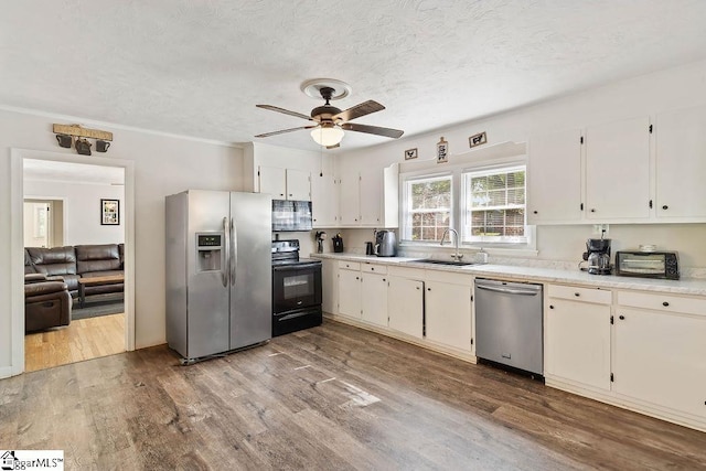 kitchen featuring wood finished floors, stainless steel appliances, light countertops, a ceiling fan, and a textured ceiling