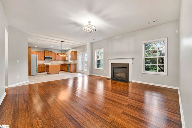 unfurnished living room featuring baseboards, a wealth of natural light, and light wood-style flooring