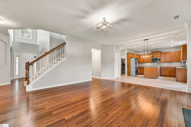 unfurnished living room featuring stairway, visible vents, baseboards, recessed lighting, and light wood finished floors