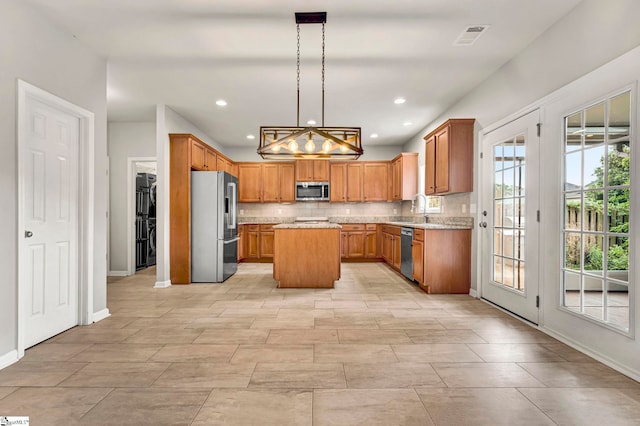 kitchen with a sink, appliances with stainless steel finishes, a kitchen island, baseboards, and backsplash